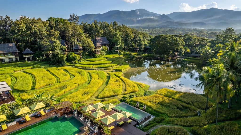 Luxurious infinity pool overlooking lush green rice terraces and mountains at Four Seasons Resort Chiang Mai, surrounded by tropical foliage