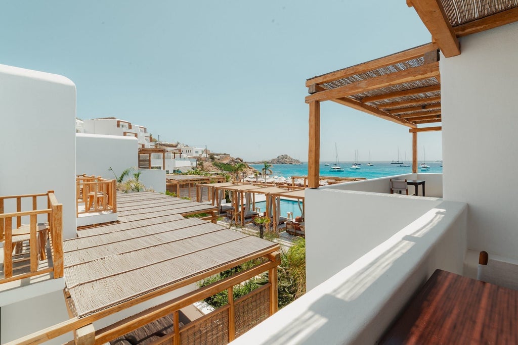 Luxurious junior suite with minimalist white decor, panoramic sea view, private balcony, and elegant Cycladic design overlooking azure Aegean waters at Branco Mykonos