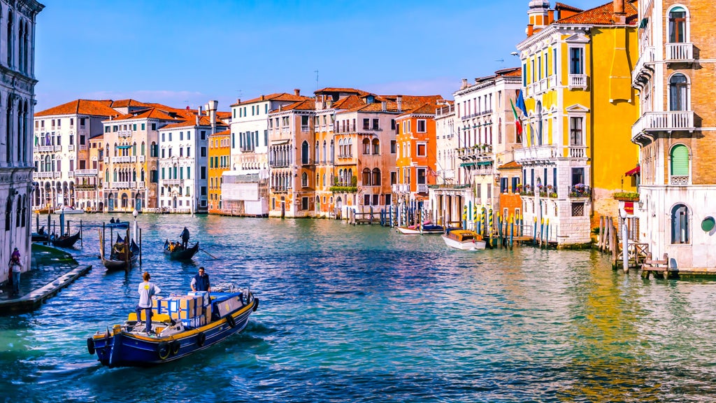 Traditional Venetian gondola gliding through narrow canal, ornate gold-trimmed seats, skilled gondolier in striped shirt, historic buildings lining waterway