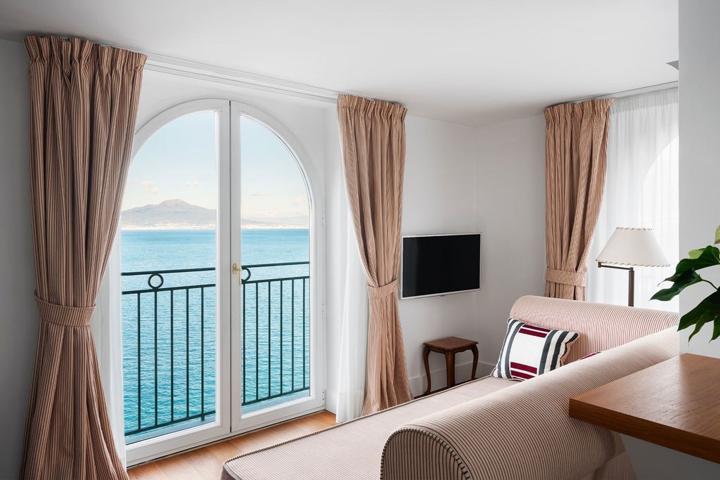 Elegant luxury suite overlooking the Bay of Naples, featuring ornate Italian design, antique furnishings, and panoramic Vesuvius views through grand windows