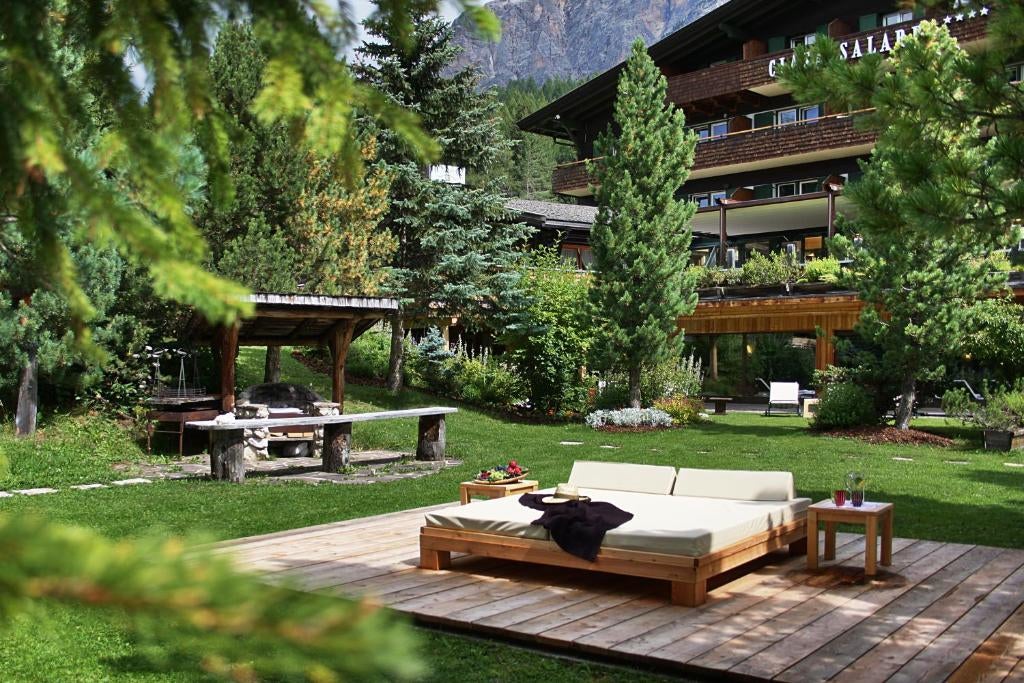 Elegant stone and wood Hotel Ciasa Salares nestled in Italian Dolomites, featuring traditional Alpine architecture and snow-capped peaks