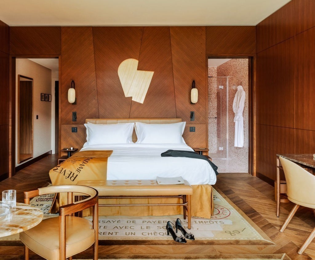 Elegant Junior Suite with modern Art Deco decor, luxurious king bed, velvet armchairs, and floor-to-ceiling windows in beige tones