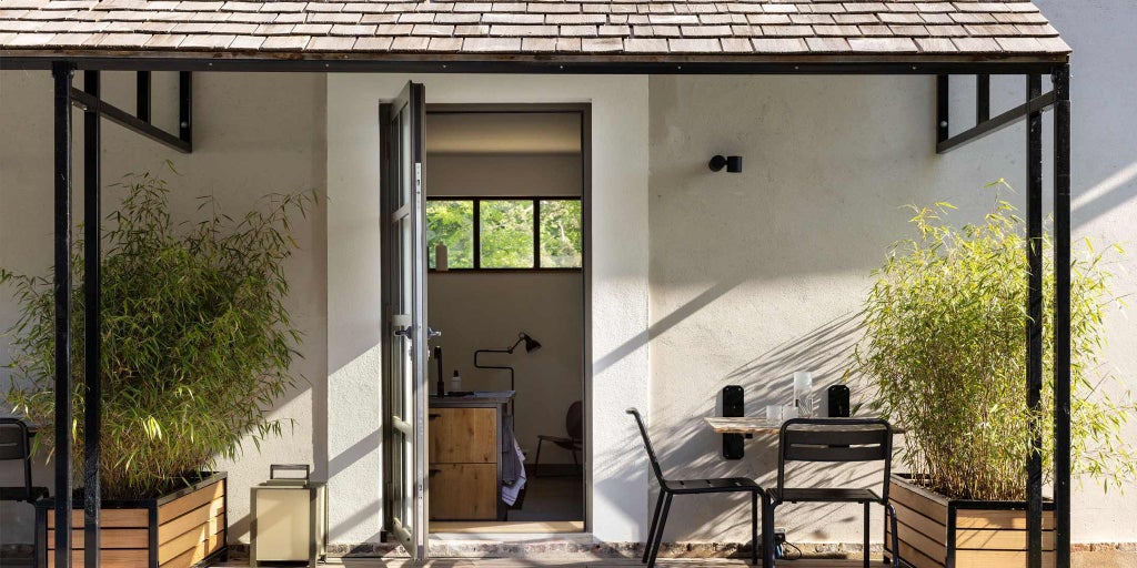 Minimalist luxury suite with white walls, designer furniture, large windows overlooking French countryside, blending modern elegance with rustic Burgundy charm at Château de la Resle