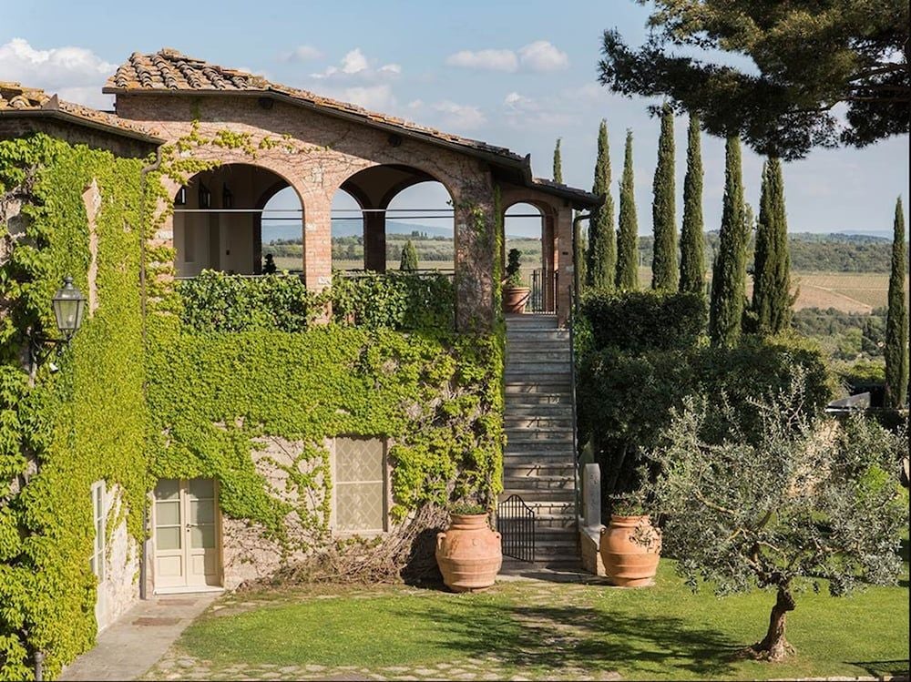 Elegant Tuscan luxury hotel with stone buildings nestled among cypress trees, featuring a scenic courtyard and classic Italian architecture