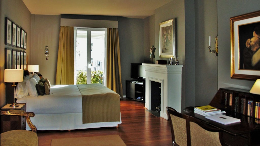 Elegant boutique hotel suite featuring dark wood furnishings, plush red armchairs, and ornate local decor in warm lighting