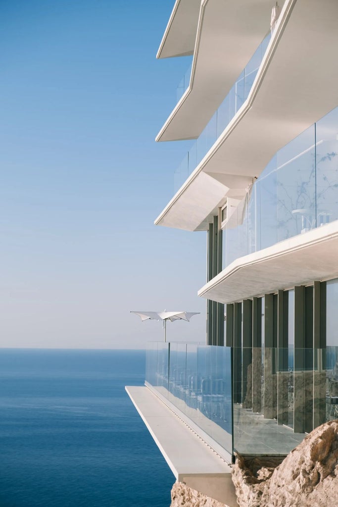 Sleek modern luxury hotel perched on French Riviera cliffside, featuring minimalist architecture and panoramic Mediterranean views