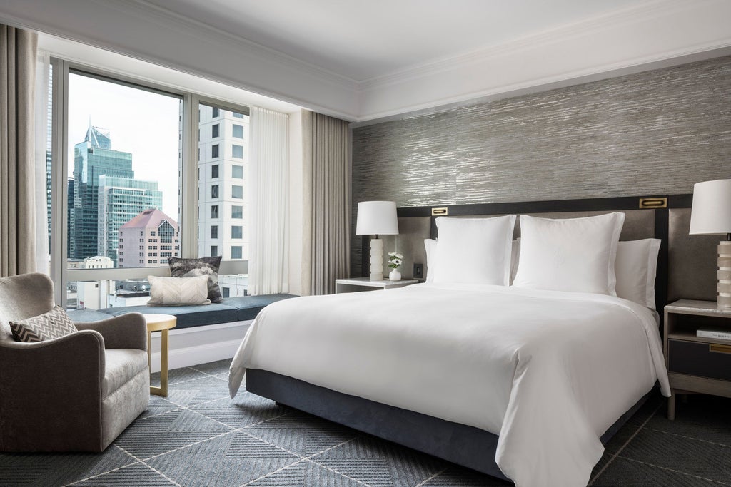 Modern luxury hotel tower with floor-to-ceiling windows reflecting cityscape, overlooking San Francisco Bay and downtown skyline