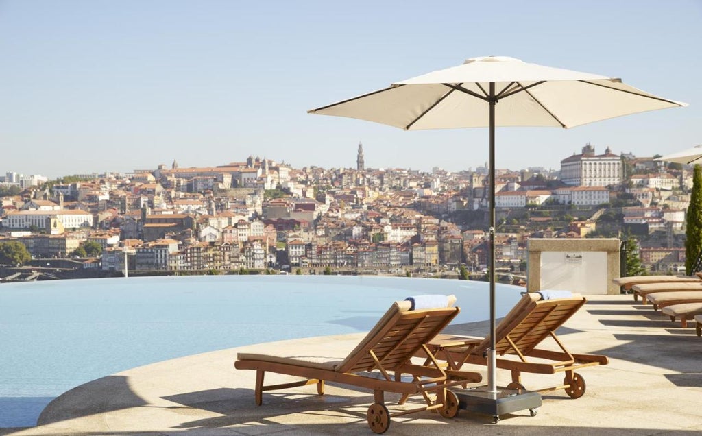 Luxurious infinity pool overlooking Porto's historic riverfront, with terraced gardens and panoramic views of Douro River at sunset