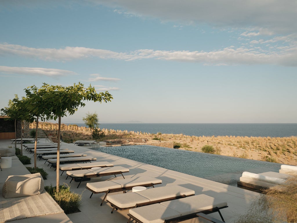 Elegant white villa with private infinity pool overlooking the Mediterranean Sea, surrounded by traditional Greek architecture at dusk