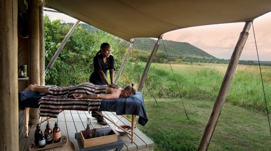 Luxurious safari tent overlooking vast Kenyan savanna with grazing wildlife, golden grasslands, and distant acacia trees at andBeyond Kichwa Tembo camp