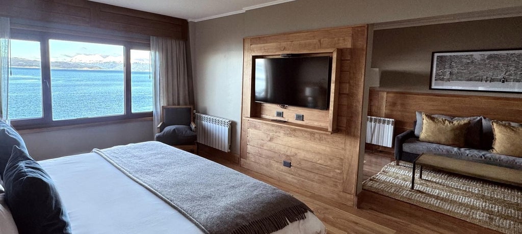 Luxurious junior suite overlooking Beagle Channel, featuring elegant décor, plush bedding, and panoramic windows with stunning Argentinian landscape views