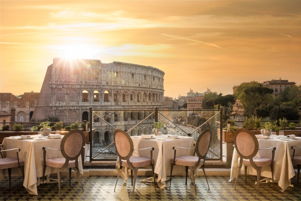 Elegant rooftop restaurant at Hotel Palazzo Manfredi with candlelit tables overlooking illuminated Colosseum against Rome's evening sky