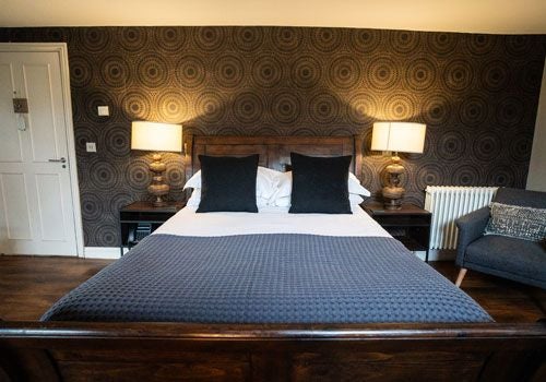 Elegant boutique hotel room with plush white bedding, vintage wooden furnishings, and soft natural light at Yorebridge House luxury accommodation in the UK