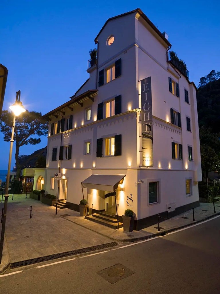 Modern boutique hotel in Italy with elegant stone facade, arched windows, and wrought iron balconies adorned with climbing vines