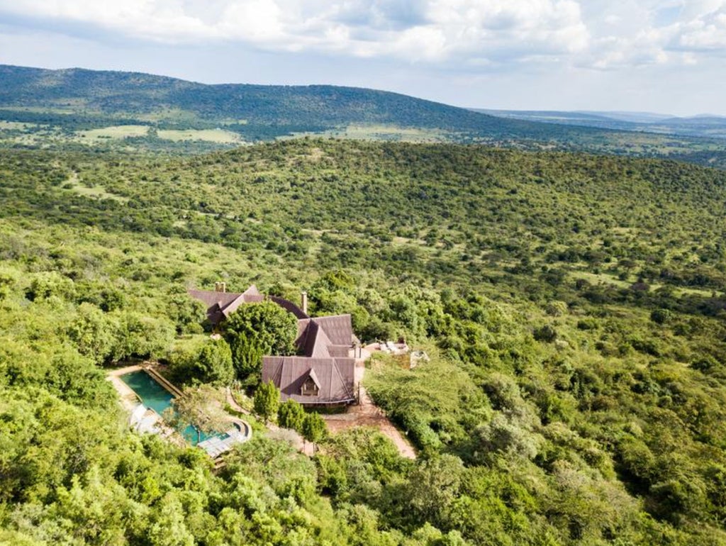 Elegant white canvas safari tent with colonial furnishings overlooks vast Kenyan savanna at sunrise, vintage-style luxury ambiance