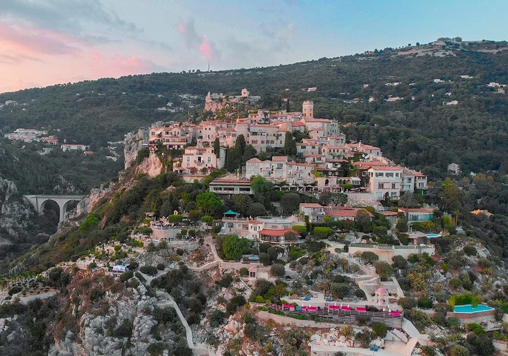 Mediterranean cliffside luxury hotel with stone terrace overlooking azure sea, white balustrades and elegant garden in Eze, France