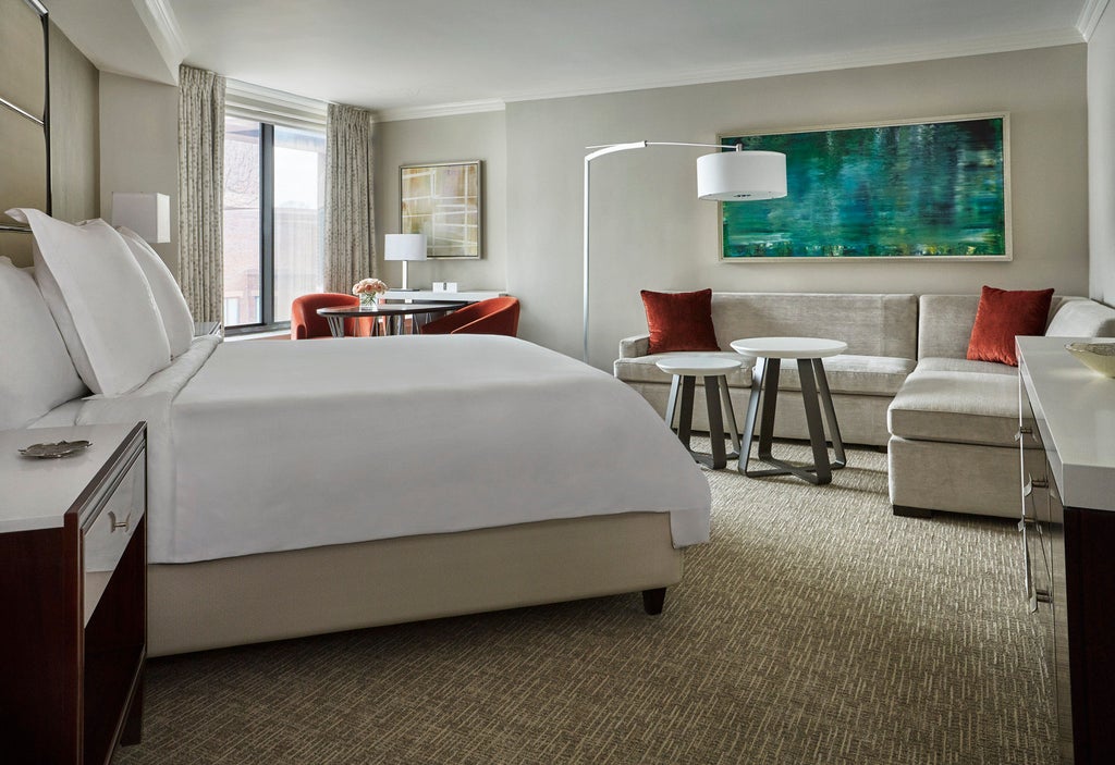 Modern, luxury hotel facade with red brick exterior, elegant arched windows, and manicured greenery in the heart of Georgetown, Washington DC