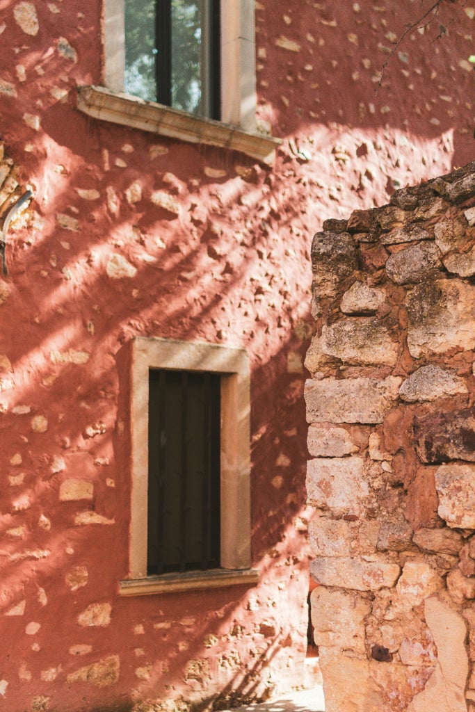 Sunlit provençal village perched on hilltop with stone houses, terracotta roofs, and lavender fields stretching into Luberon Valley