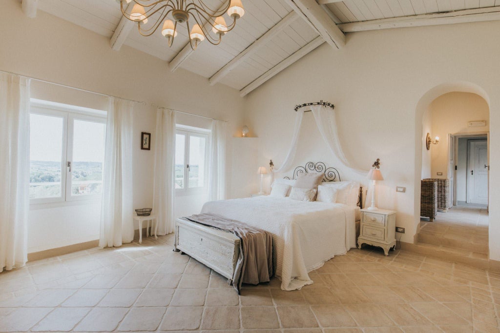 Elegant Italian suite with plush white bedding, marble-tiled floor, modern minimalist decor, and panoramic window overlooking scenic landscape