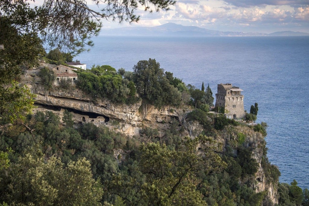 Medieval watchtower villa perched on Amalfi cliffs with terraced gardens, sea views, antique furnishings across four luxury a