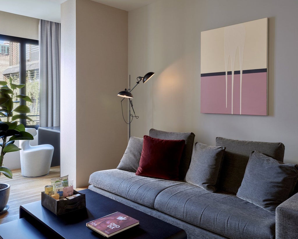 Elegant modern hotel room with sleek wooden furniture, minimalist design, warm neutral tones, and expansive city view from large floor-to-ceiling windows in Barcelona, Spain