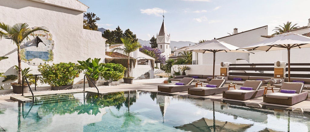 Luxurious white and beige Nobu Hotel exterior with modern minimalist architecture, palm trees, and elegant poolside setting in Marbella, Spain