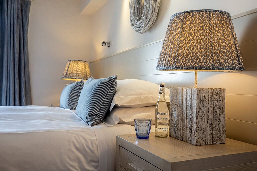 Cozy coastal village room at the St Mawes Hotel, featuring crisp white linens, sea-inspired decor, and panoramic views of the Cornish coastline