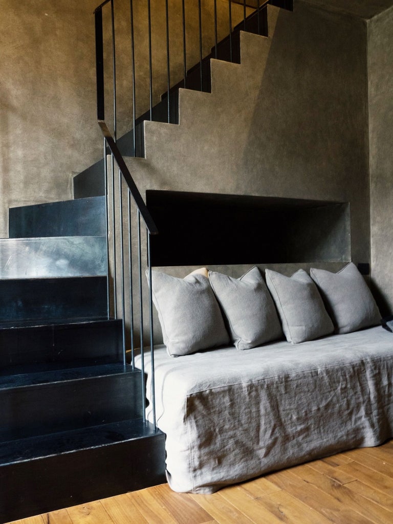 Elegant hotel suite with exposed stone walls, rustic wooden beams, and a plush king bed draped in premium white linens