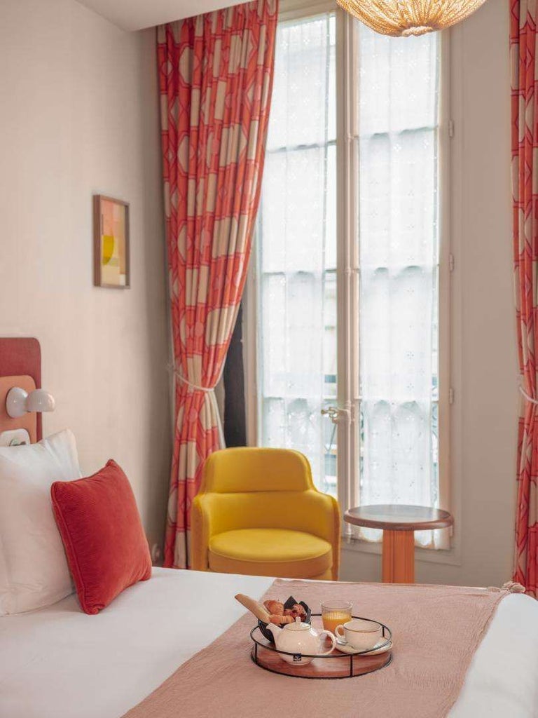 Elegant Parisian boutique hotel facade with historic stone exterior, wrought-iron balconies, and charming street-level windows in Saint-Germain-des-Prés