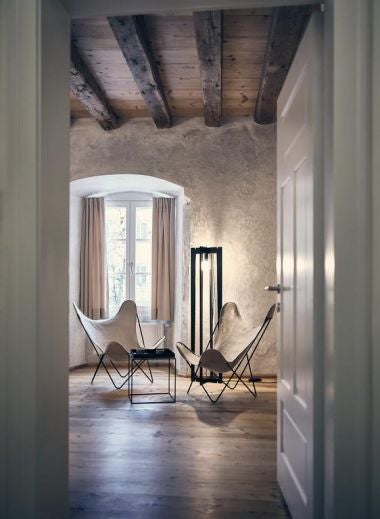 Modern boutique hotel exterior with wood and glass facade, illuminated entryway, and traditional Austrian architectural elements at dusk