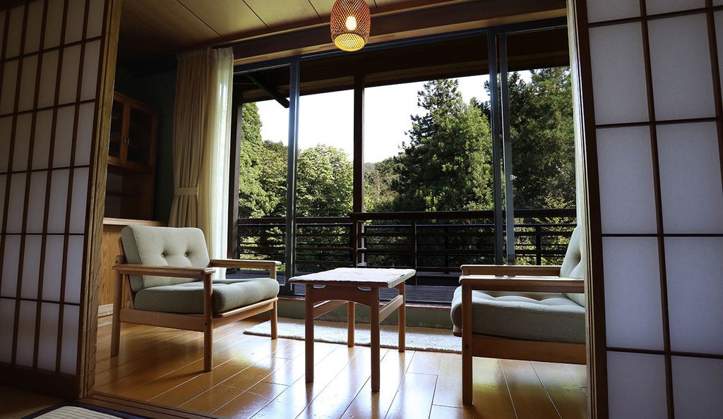 Traditional Japanese-style luxury suite with elegant wood furnishings, tatami mat flooring, and private open-air stone bath overlooking serene scenic landscape