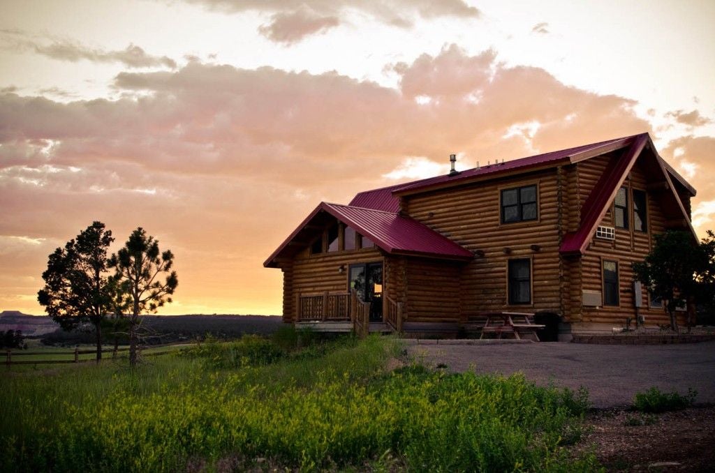 Rustic-style lodge room with wooden furnishings, plush bedding, and panoramic mountain views of a scenic landscape near a national park