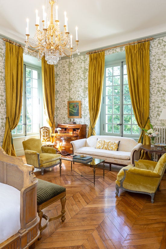 A luxurious corner king room with grand French windows, antique furnishings, elegant crown molding and panoramic countryside views of Loire Valley