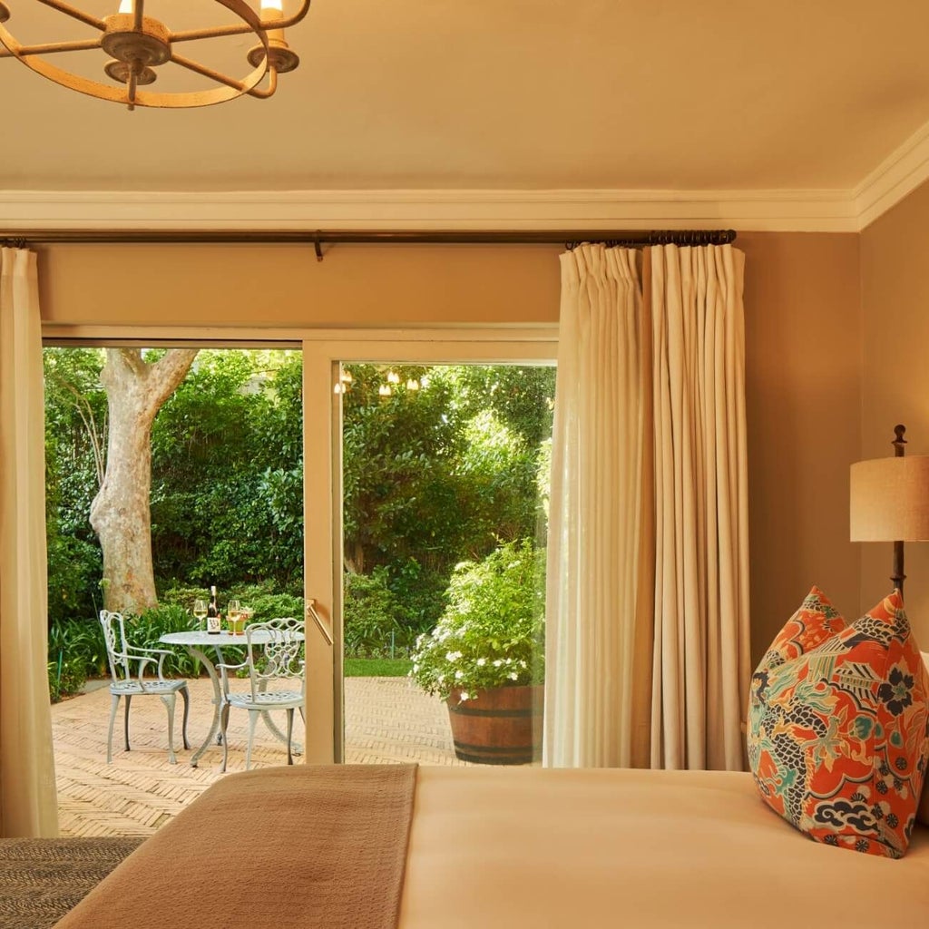 Luxurious pool suite with crisp white linens, elegant wooden furnishings, and sliding glass doors overlooking a serene landscaped garden in South Africa