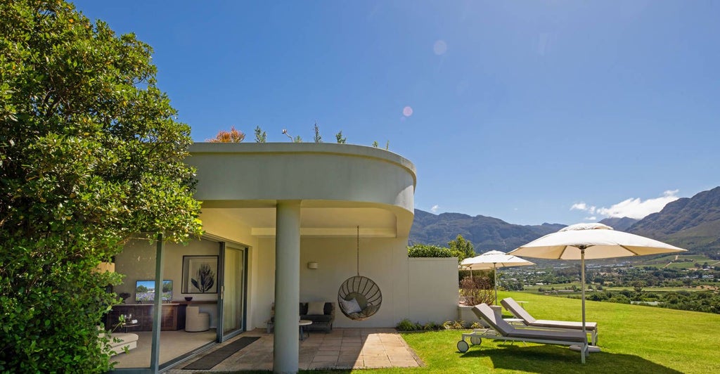 Luxurious king bedroom at Mont Rochelle with elegant wine-inspired decor, plush white linens, and panoramic vineyard views in South African wine country