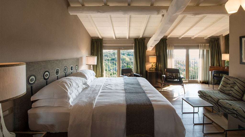 Elegant Tuscan-style hotel room with soft neutral tones, wooden furniture, and large windows overlooking rolling Italian countryside hills