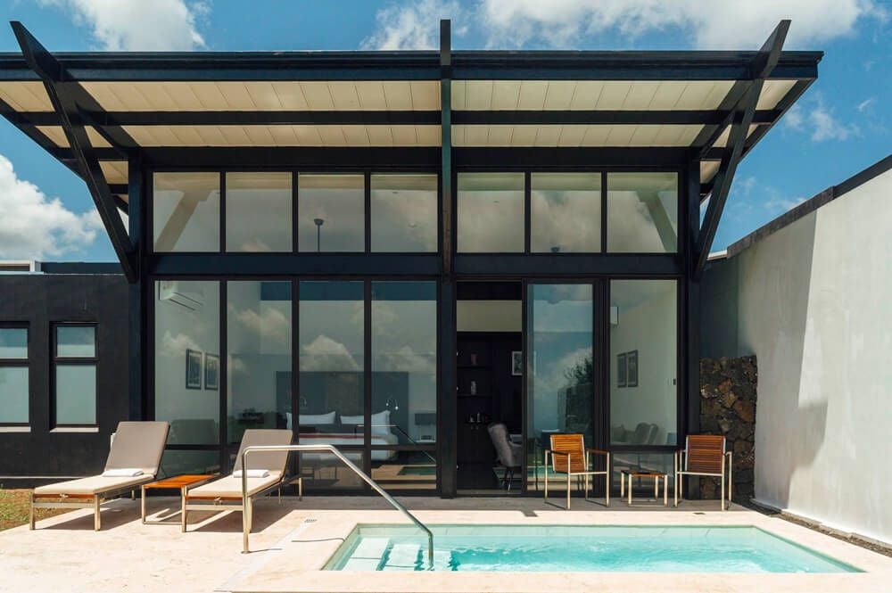 Luxurious pool suite at Pikaia Lodge with modern design, featuring sleek infinity pool overlooking lush Ecuadorian landscape at sunset