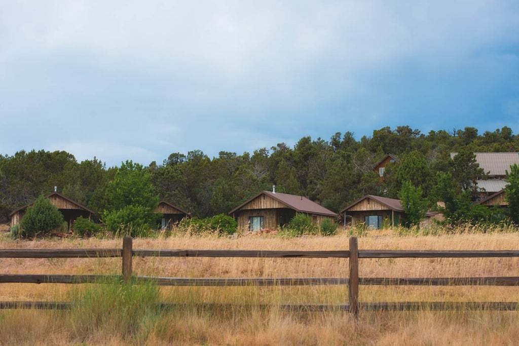 Rustic log cabin bedroom with warm wood tones, cozy king bed, panoramic mountain views, and elegant southwestern decor at Scenset Mountain Ranch.