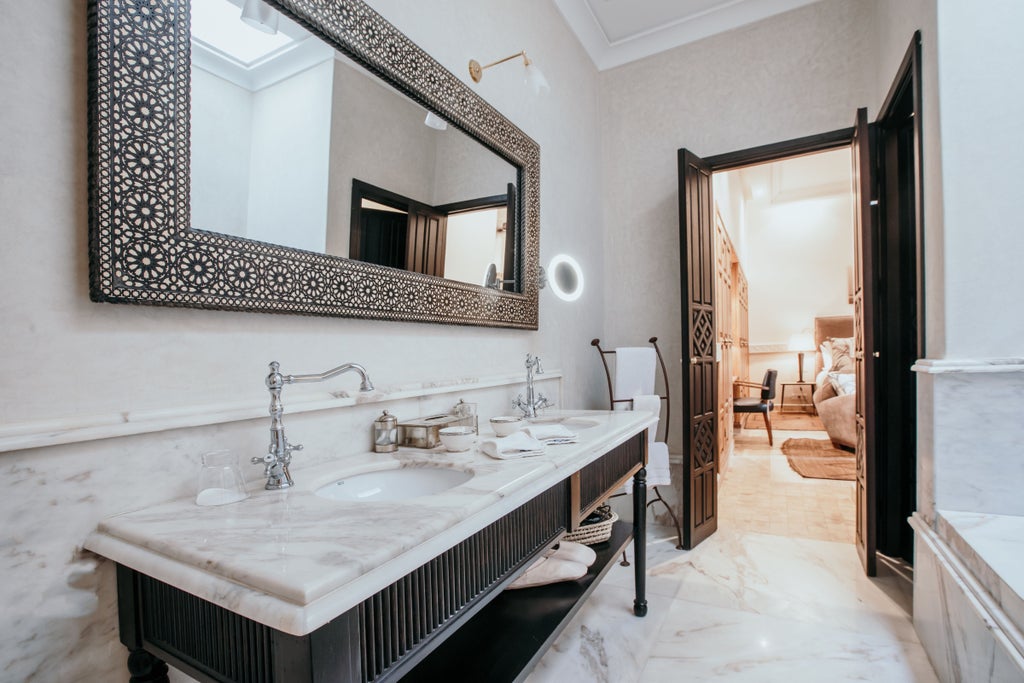 Elegant Moroccan riad with traditional archways and reflecting pool surrounded by potted citrus trees and ornate loungers at sunset