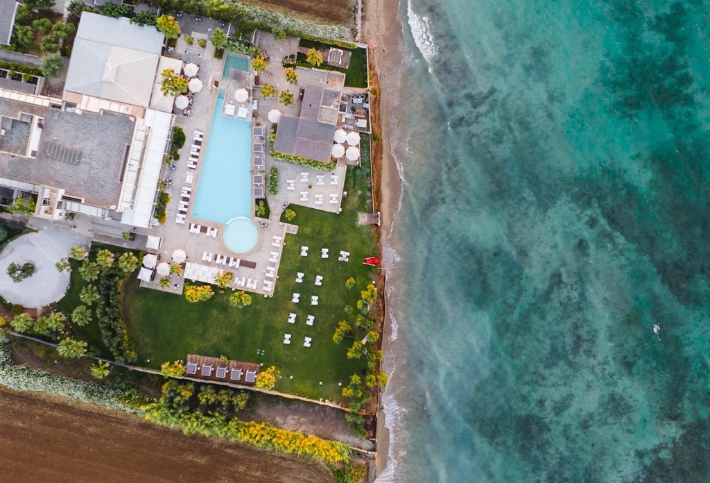 Elegant white-washed luxury hotel with minimalist design, azure pool, and sun loungers overlooking lush Mediterranean landscape in coastal Italy