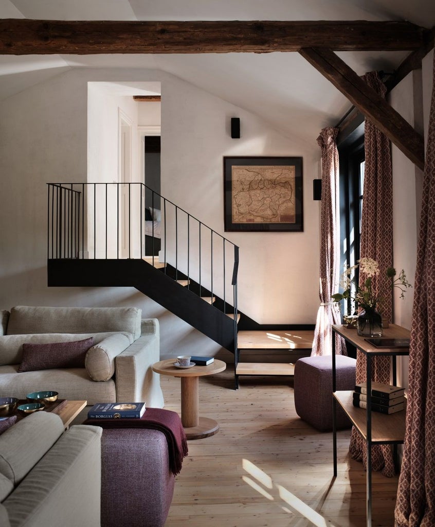 Luxurious rustic bedroom in Transylvanian stone house with wooden beams, plush white bedding, vintage furnishings, and panoramic countryside view through large window