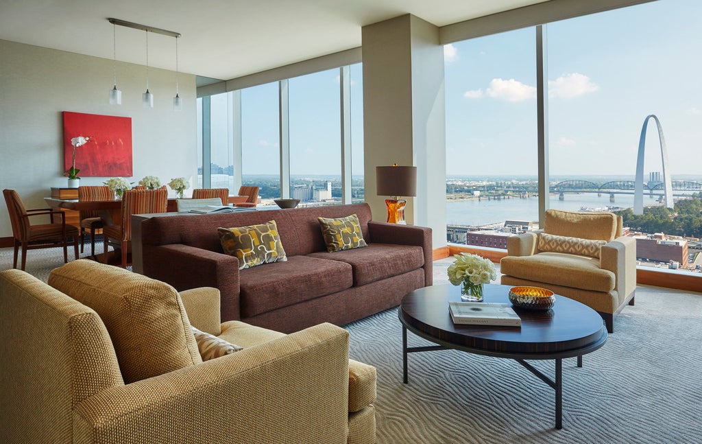 Elegant modern glass hotel tower with curved facade, rooftop terrace and infinity pool overlooking St. Louis city skyline at sunset