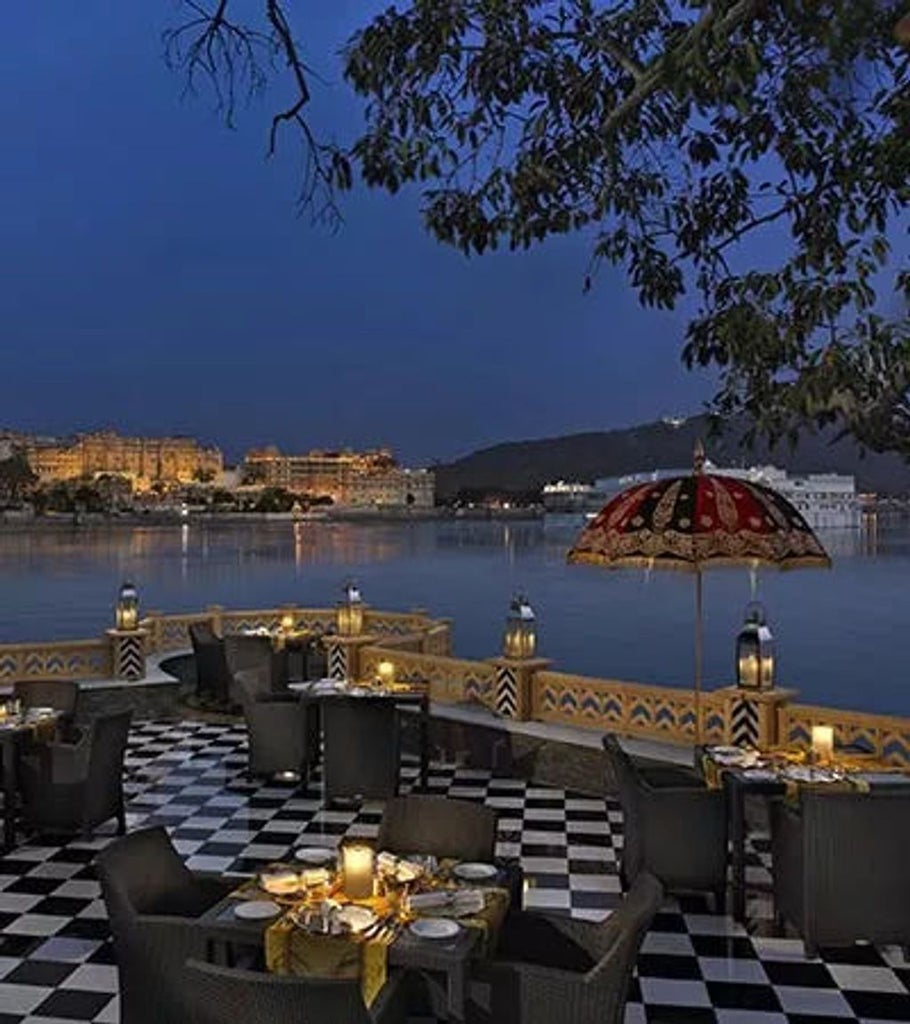 Opulent lakeside palace hotel with white marble domes and arches, reflecting in Lake Pichola against backdrop of Aravalli mountains