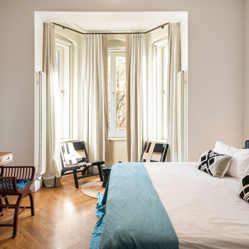 Modern minimalist hotel room with sleek white furnishings, wooden floor, large window, and elegant contemporary design in Gorki Apartments, Germany