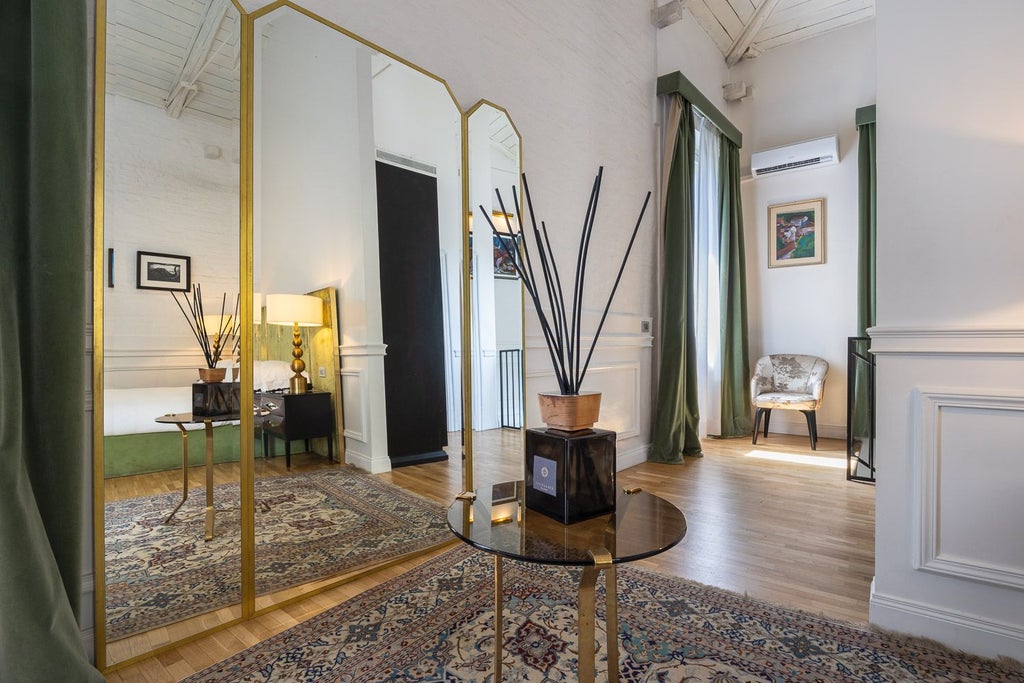 Luxurious garden suite at Palazzo Dama with plush white bed, elegant marble decor, and sliding doors opening to a lush green private terrace in Italy.