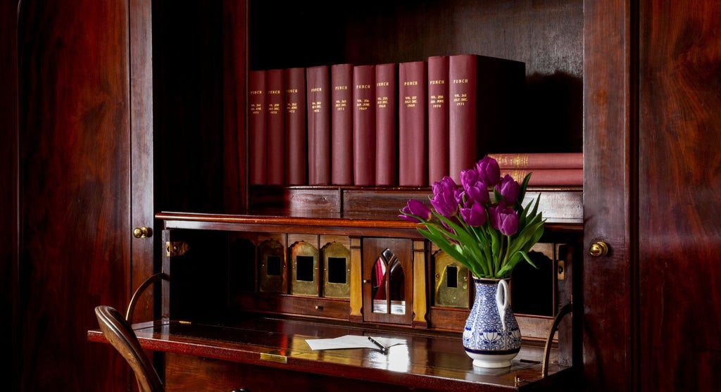 Opulent club double hotel room with elegant dark wood furnishings, plush bedding, and sophisticated mood lighting in historic United Kingdom setting