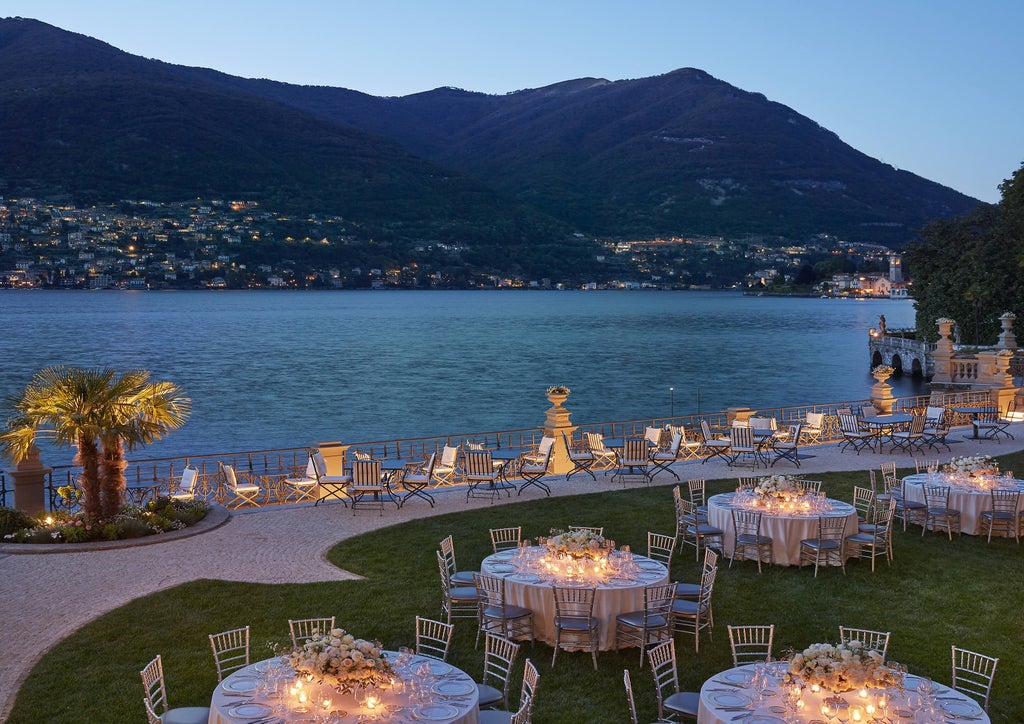 Luxurious infinity pool overlooking Lake Como at sunset, with snow-capped Alps in background and elegant lounge chairs along deck