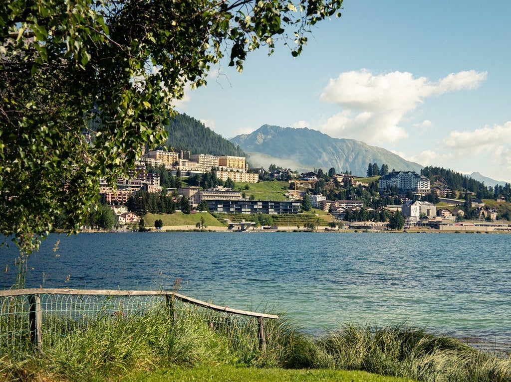 Historic alpine luxury hotel in St. Moritz with Belle Époque architecture, overlooking snow-capped mountains and a pristine mountain lake