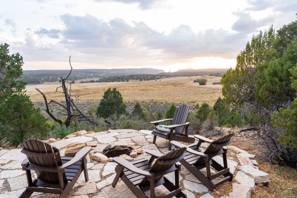 Rustic lodge room with wooden furnishings, plush bedding, and large windows overlooking scenic mountain landscape at a tranquil ranch retreat