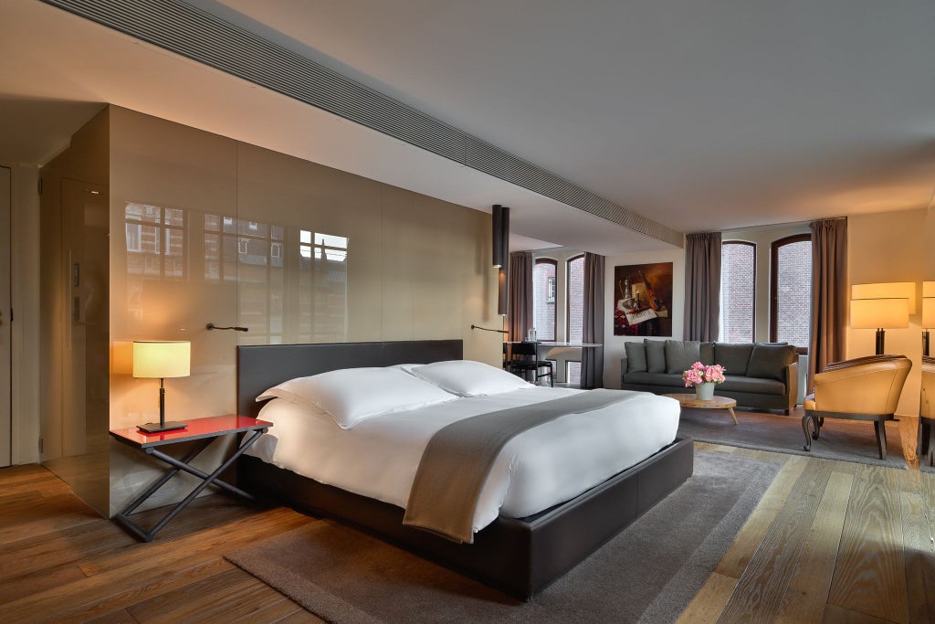 Luxurious grand junior suite at Conservatorium Hotel, Amsterdam, featuring contemporary design with elegant furnishings and large windows overlooking urban scenery